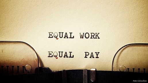 Auf einem in eine Schreibmaschine eingespannten Blatt stehen die getippten Worte "Equal Work - Equal Pay"